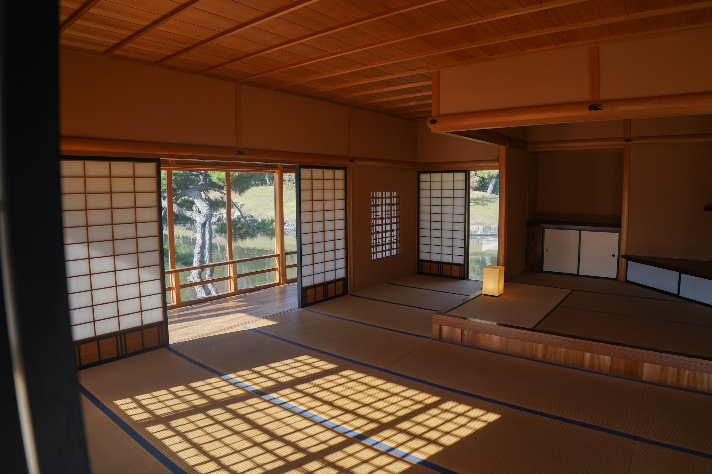 A traditional Japanese tatami room with shoji screens and a sunlit garden view